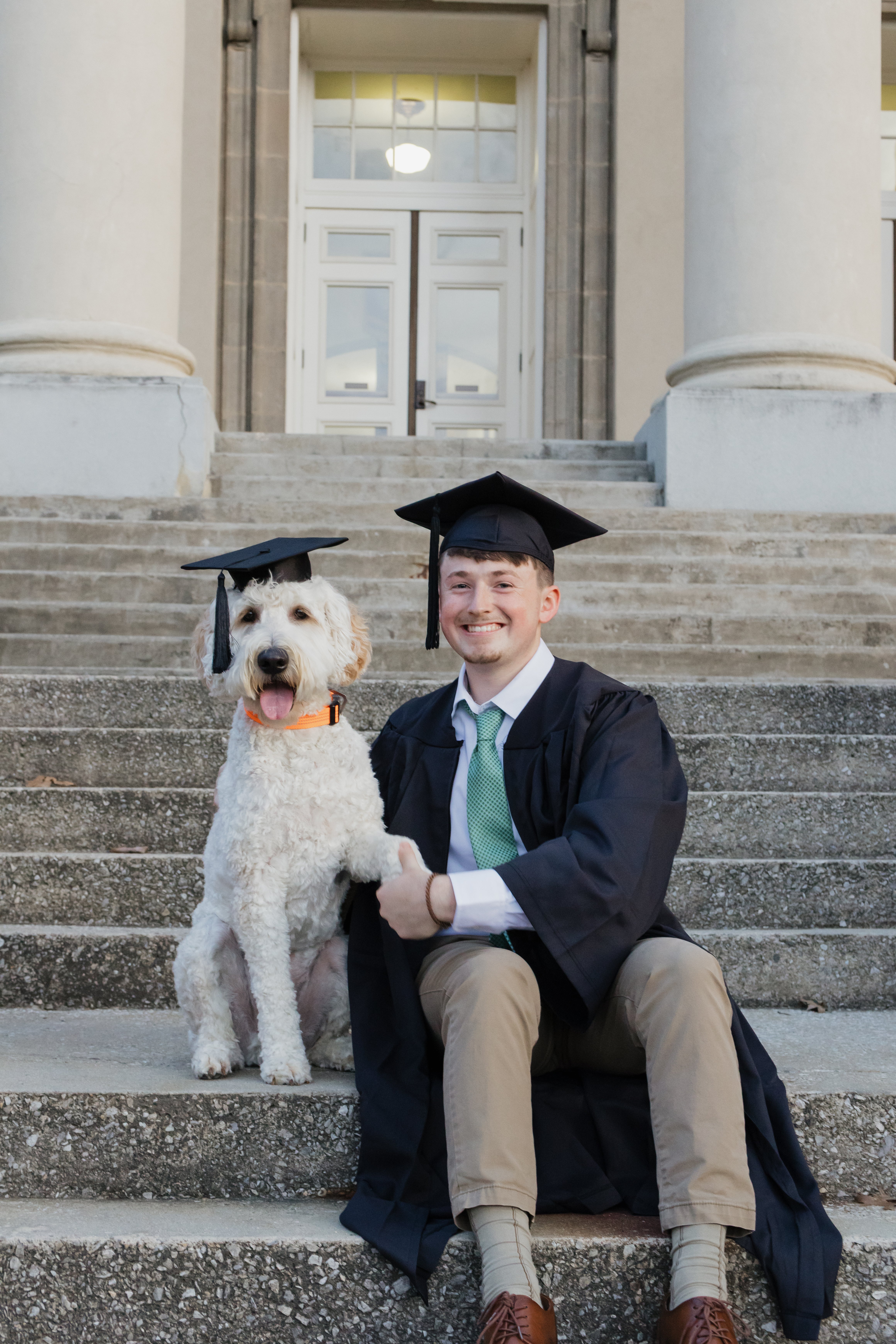 Male graduate and dog in graduation apparel